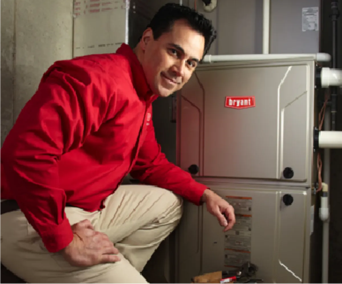 A Bryant technician beside a newly installed furnace