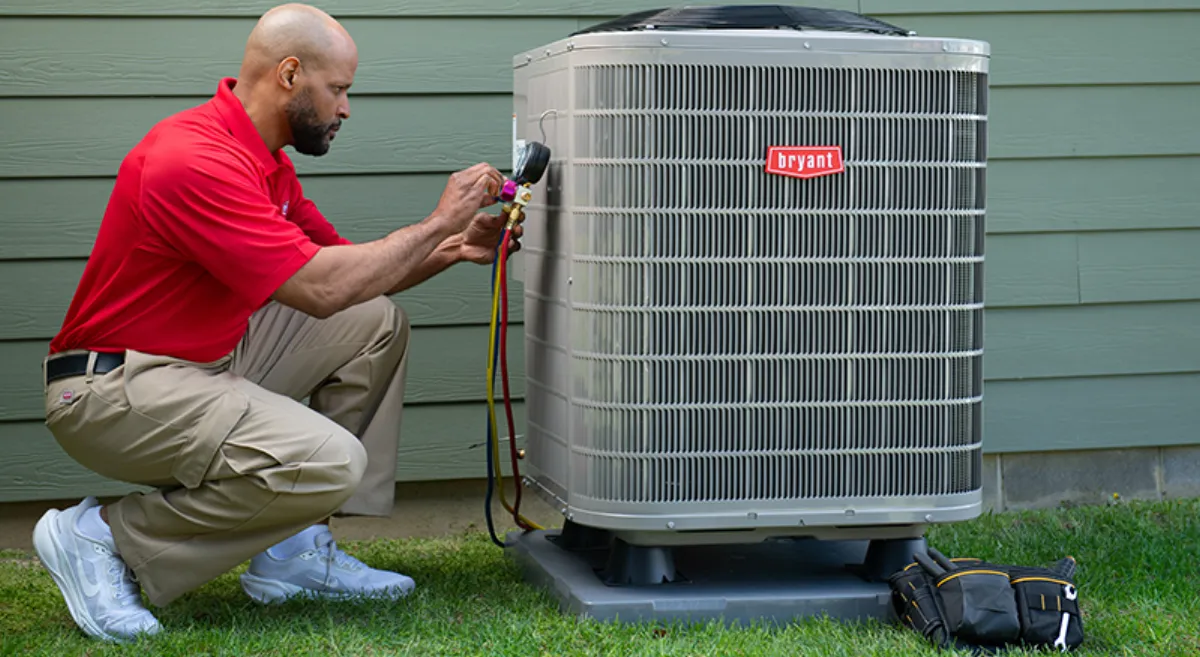 A Bryant dealer checking gauges on a heat pump outside a home